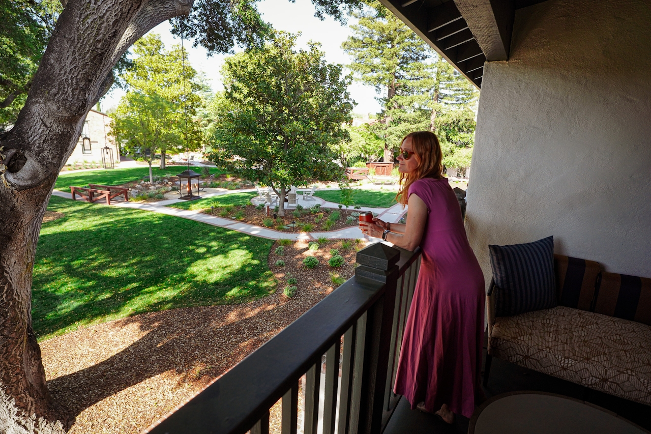 A woman looks out from her balcony room onto the sprawling green lawn at the Paso Robles In